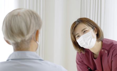 Female worker with mask talking with resident