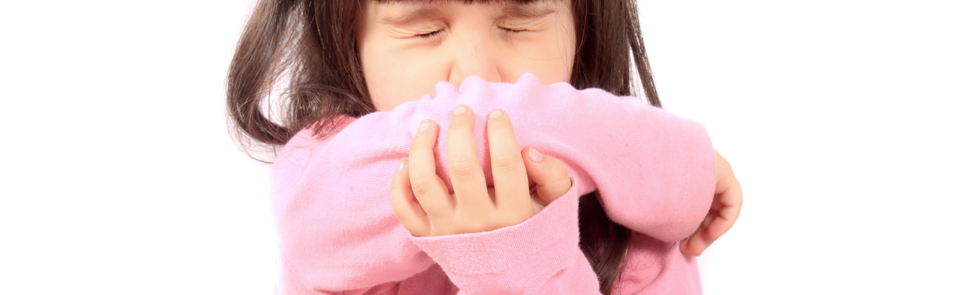 Small girl sneezing into sleeve.
